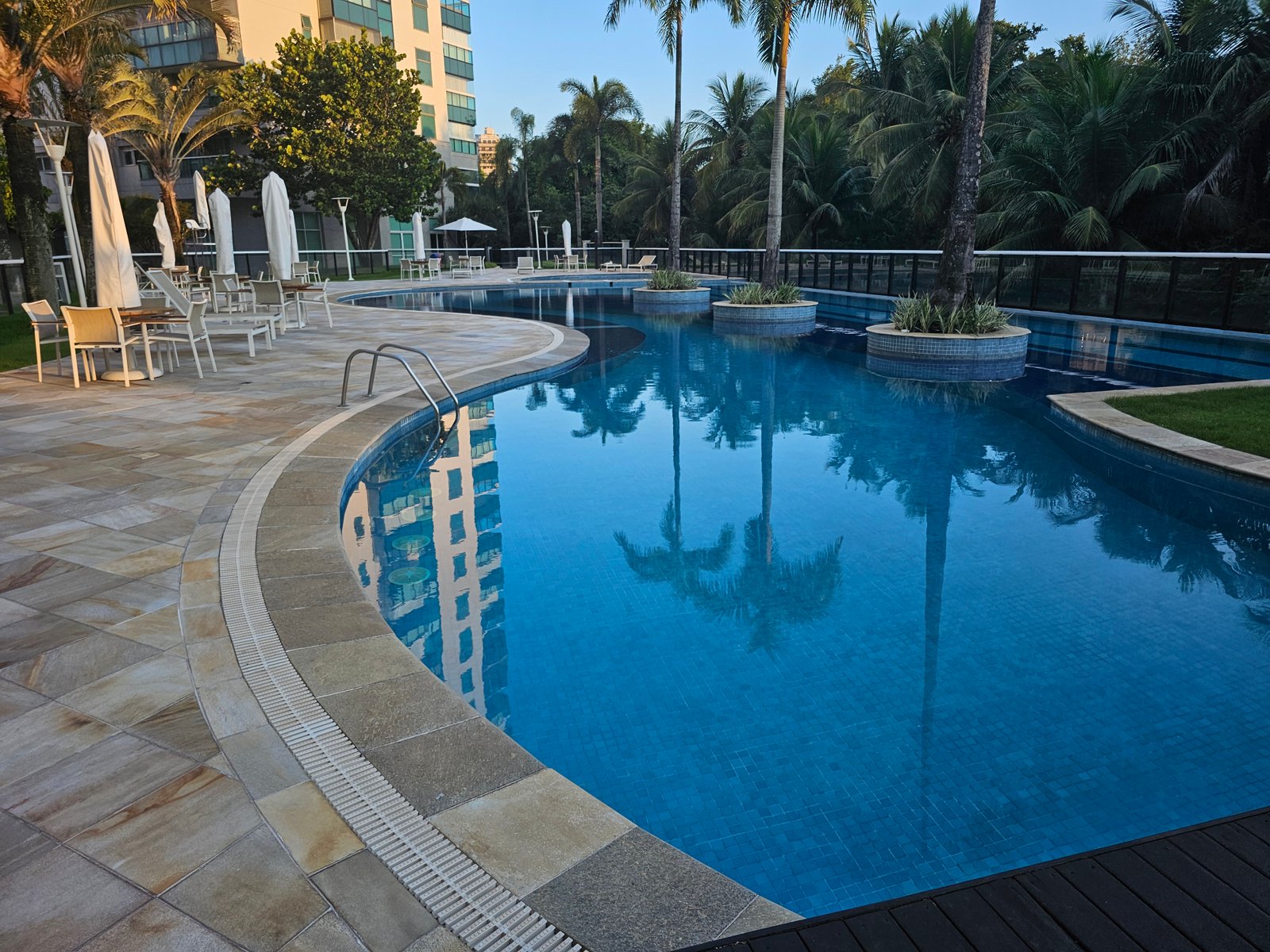 Piscina do condomínio com palmeiras tropicais