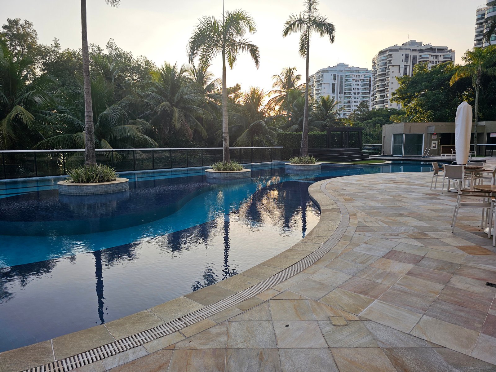 Piscina ao pôr do sol com palmeiras