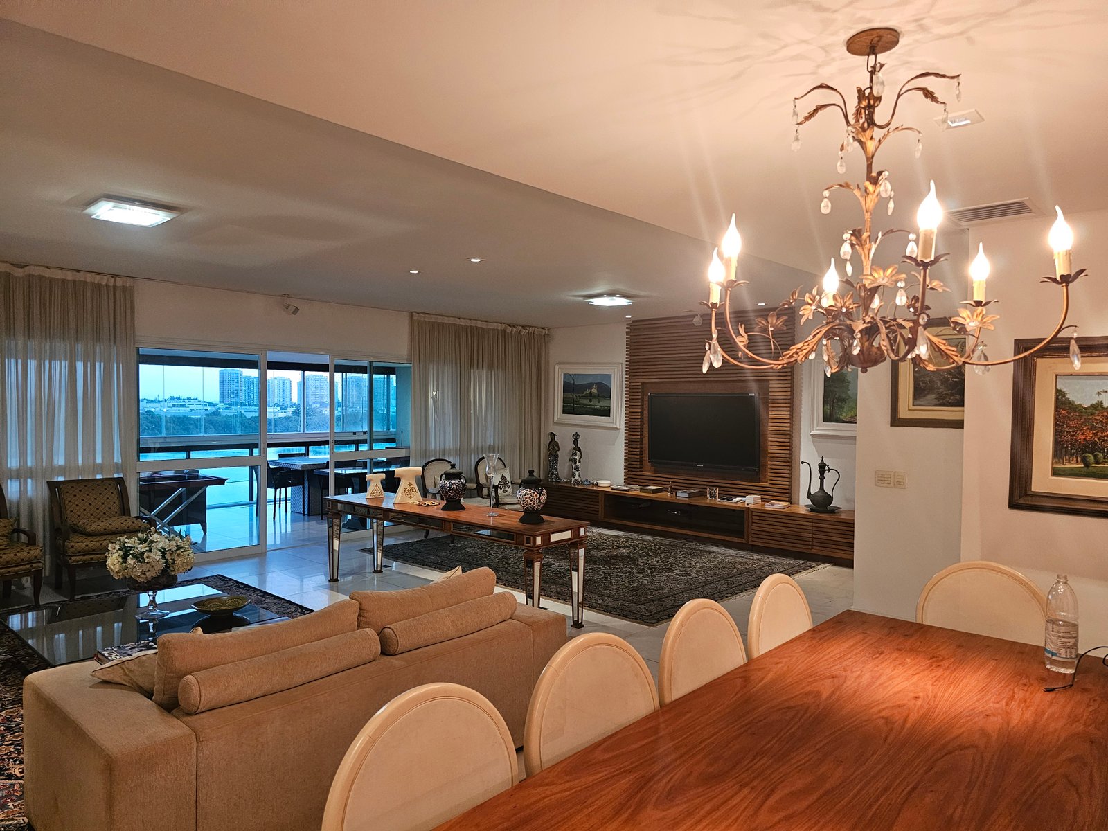 Sala de estar integrada com sala de jantar, lustre e vista para a Península