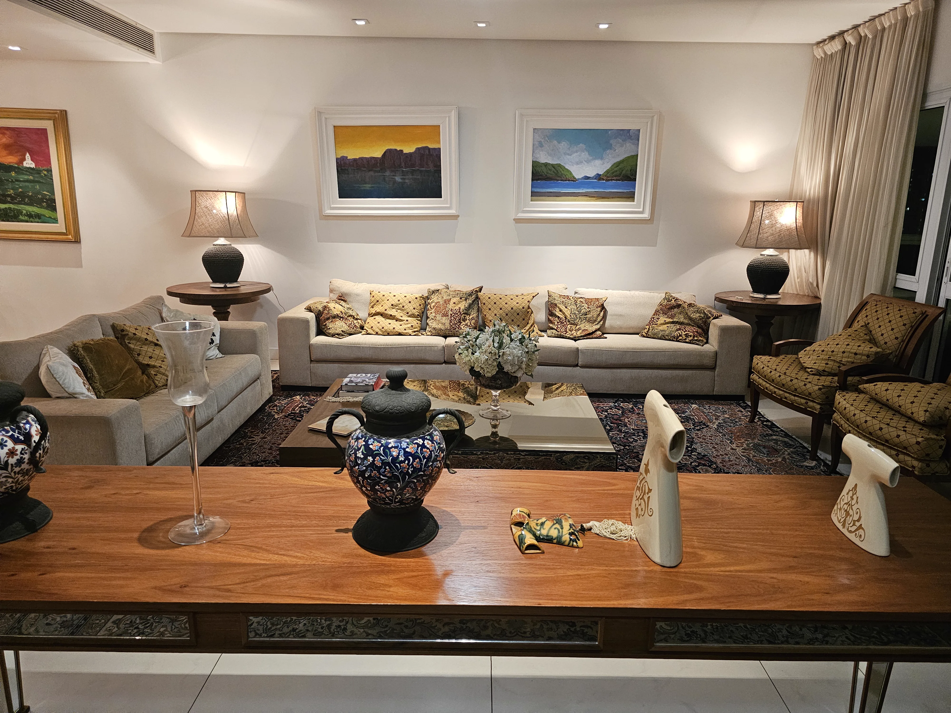 Sala de estar com sofás, quadros e mesa lateral decorada